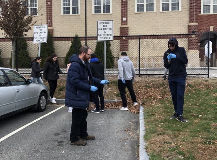 Alex Millar and Mr. Chase examine some trash they found in the student parking lot.