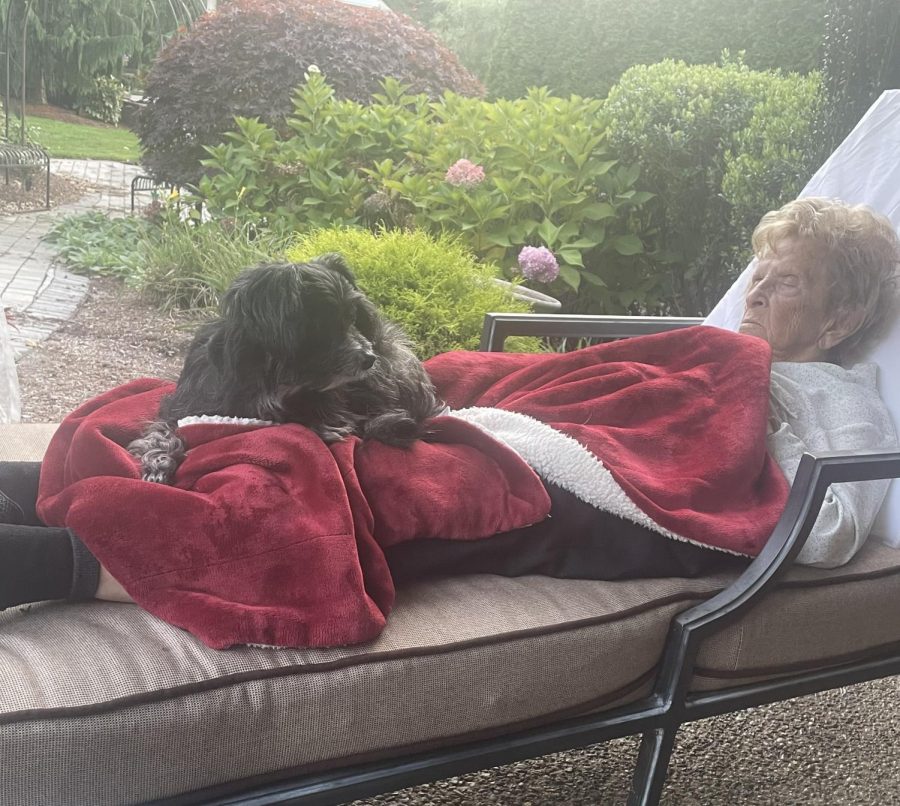 Claire Lopes asleep on her patio with her dog, Silky, resting in her lap.